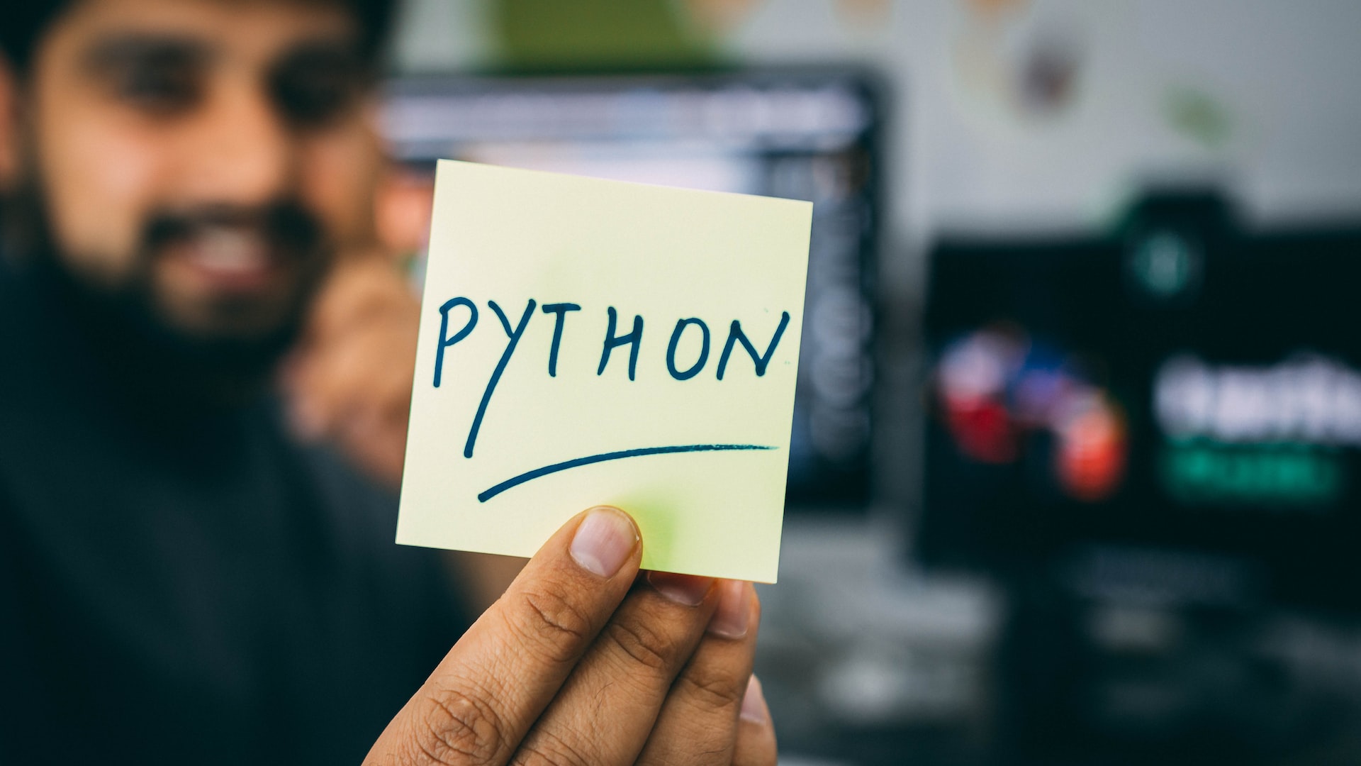 smiing man holding a sticky note with the inscription python