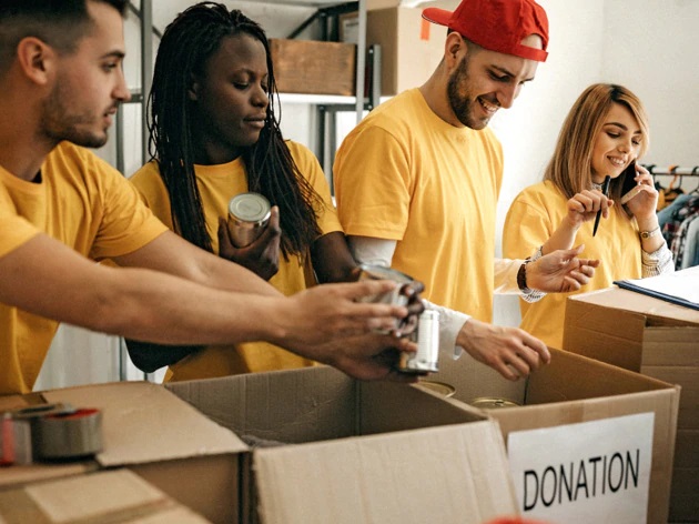 volunteers helping sort out donation items into a box, new Microsoft Cloud for Nonprofit AI features announced 